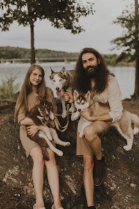 a man and woman are posing with their husky dogs